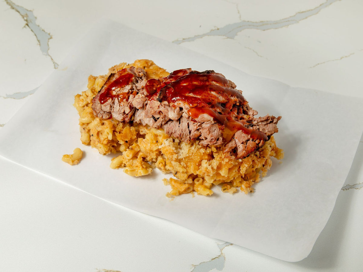 Brisket mac and cheese topped with smoked brisket and BBQ sauce at Embark Smoked Meats