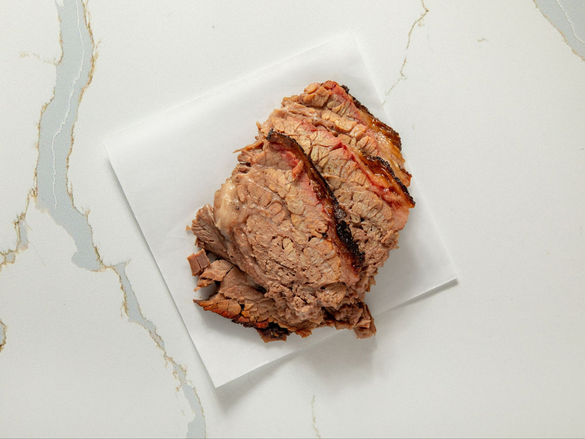 Sliced smoked brisket with dark peppery bark from Embark Smoked Meats in Boonton, NJ
